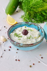Homemade Greek traditional sauce tzatziki with cucumber, garlic, yogurt , olive oil and lemon in a traditional colored bowl on a white background. Healthy eating concept. Mediterranean lifestyle