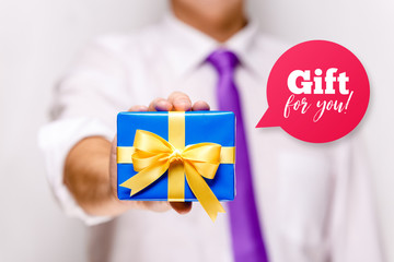 Male hand holding a gift box. Present wrapped with ribbon and bow. Gift for you speech bubble. Man in white shirt and necktie.