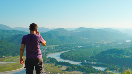 Naklejka premium Man talking on a mobile phone on a mountain landscape background