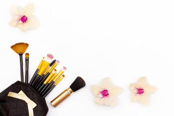 Obraz na płótnie Canvas makeup brushes and few flowers Orchid on a white background. Concept of beauty. Flat lay.