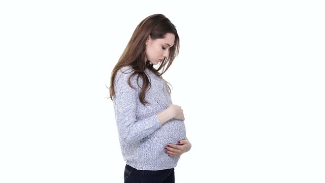 Upset young pregnant woman touching her belly and looking at camera isolated over white