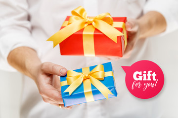 Male hands holding a gift boxes. Present wrapped with ribbon and bow. Gift for you speech bubble. Man in white shirt.