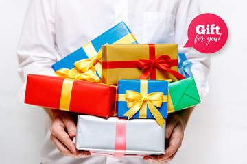 Male hands holding a gift boxes. Presents wrapped with ribbon and bow. Gift for you speech bubble. Man in white shirt.