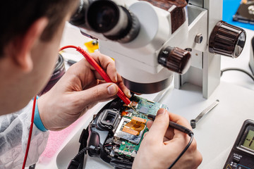 Close up hands of a service worker repairing digital camera.