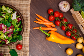 Provence salad. Leaves of endive or chicory, lamb and rose salad. Cherry tomatoes, pepper and carrot. Raw vegetables. On wooden table.
