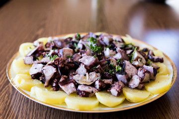Insalata di polpo con patate e prezzemolo su un piatto tondo