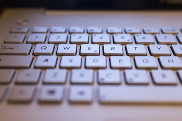 A qwerty keyboard focused on QWERTY keys. Monitor light illuminate keyboards keys