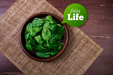 Spinach leaves in bowl. Raw fresh vegetable. Fresh natural plant leaf. Organic bio food on rustic wooden table.