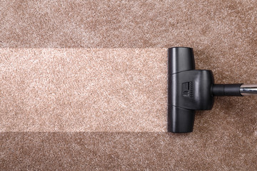 Vacuuming carpet with vacuum cleaner. Housework service. Close up of the head of a sweeper cleaning device.