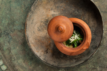 dish in a clay pot on an old antique tray