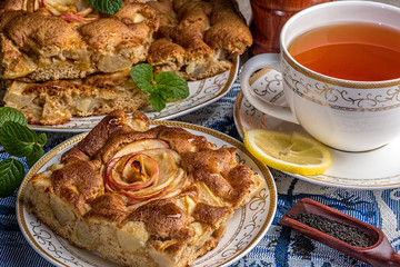 Apple pie on a porcelian plate with mint and cup of tea.