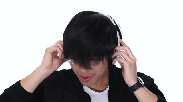 Excited young asian man enjoys listening to music with headphones on a white background