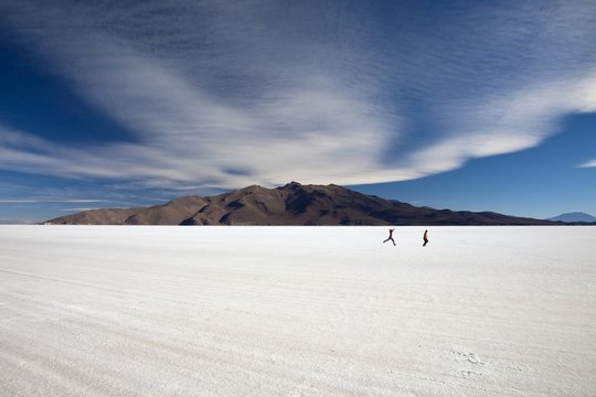 Two people run on the surface of Salar de Uyuni the largest salt desert in the world. South Lipez. Bolivia. South America