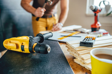 Fototapeta premium Power drill and Man using hammer in the background