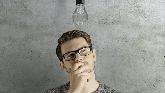 Clever creative man think gets an idea, which lights up a symbolic lamp over his head on natural background