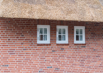 Drei kleine Fenster in einem Reetdachhaus
