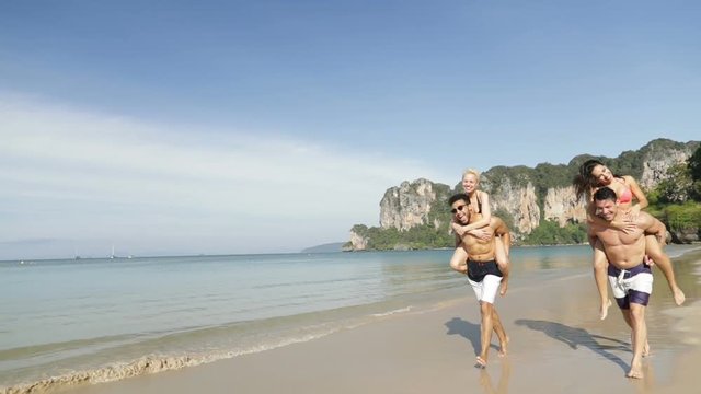 Women Ride Men Running On Beach In Mountains, Two Happy Smiling Couple Tourists Slow Motion 120