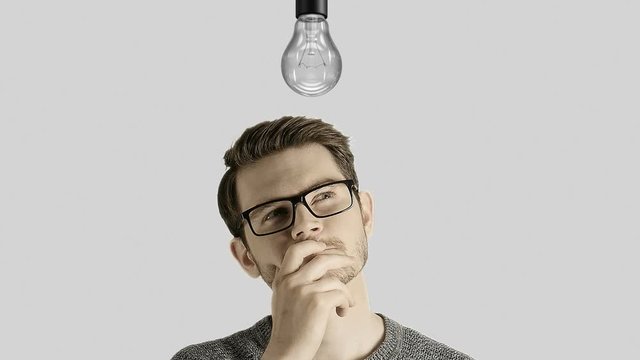 Clever creative man think gets an idea, which lights up a symbolic lamp over his head on white background