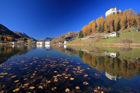 The castle of Tarasp and the lake of the namesake village of low Engadine in autumn, Switzerland Europe