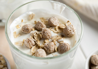 Wheat bran and oat flakes in glass with yogurt, macro