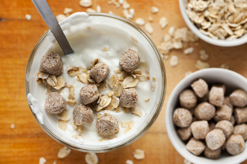 Yogurt in glass with oat flakes and wheat bran in it, selective focus, top view
