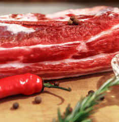 A piece of raw fresh meat with red pepper and spices on a rustic background. Is suitable for steak cooking
