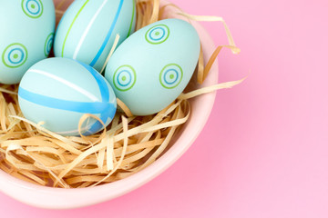 Happy easter composition. Nest with blue pained easter eggs. Texture pink background. Flat lay, top view and copyspace
