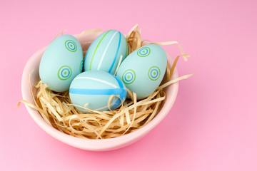 Happy easter composition. Nest with blue pained easter eggs. Texture pink background. Flat lay, top view and copyspace