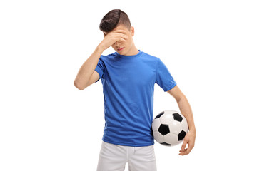 Upset teenage football player holding his head in disbelief