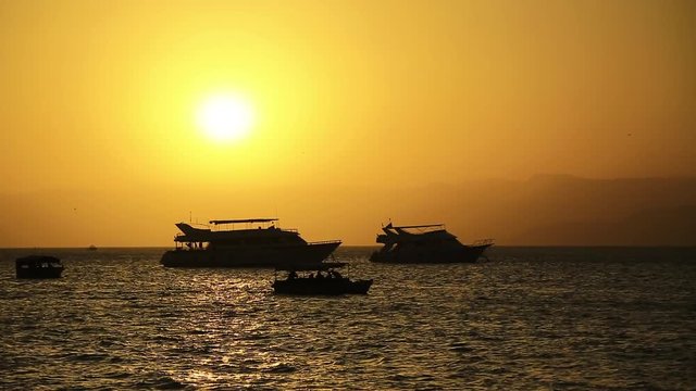 Ships in sea near Aqaba city, Hashemite Kingdom of Jordan. Red Sea, Gulf of Aqaba. Silhouettes of ships in the sea at sunset