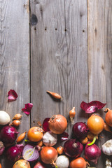 Several kinds of different onion bulbs lying on an old wooden table.