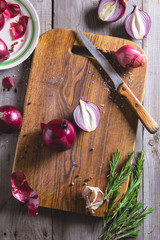 Red onion bulb on brown cutting board.