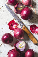 Several kinds of different onion bulbs lying on an old wooden table painted in white.