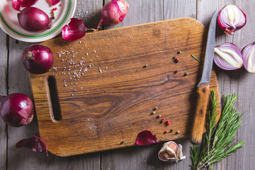Red onion bulb on brown cutting board.