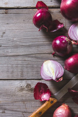 Red onion bulbs lying on an old wooden table.