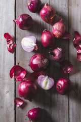 Red onion bulbs lying on an old wooden table.
