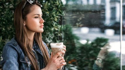 Girl holds hands cup of coffee and looking out the window. Portrait profile. Footage 16:9. Horizontal image.