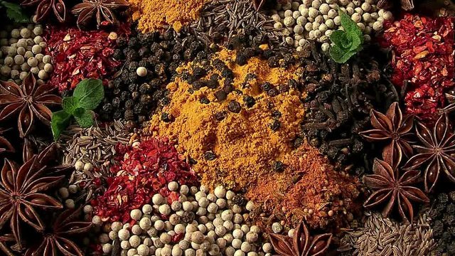 Peas of black pepper fall on spices. Red, white, black, green spices