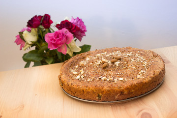 Selbstgebackenes Brot mit Nüssen, Mandeln, Amaranth, Leinsamen bestreut mit Rosen im Hintergrund