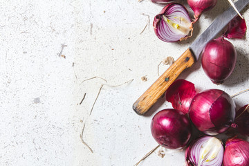 Several kinds of different onion bulbs lying on an old wooden table painted in white.