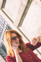 Fototapeta premium Pretty girl looking at her wrist watch in urban street.