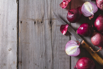 Red onion bulbs lying on an old wooden table.