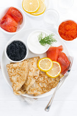 traditional Russian crepes with caviar and salted fish, top view