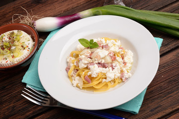 Dish of pasta noodles with cottage cheese bacon and onion shallot
