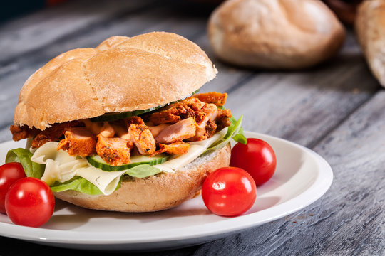 Fried Chicken Meat With Cheese And Vegetables In Bun