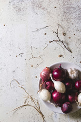 Red and white onion bulbs in the plate on old wooden painted table