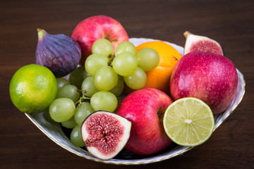 Bowl of different fruits on wooden table