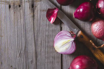 Red onion bulbs lying on an old wooden table.