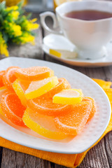 Fototapeta na wymiar A beautiful sweet marmalade, like lemon and orange slices, covered with sugar. Selective focus