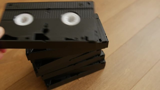 Stack of VHS video tape cassette over wooden background, top view, close up.